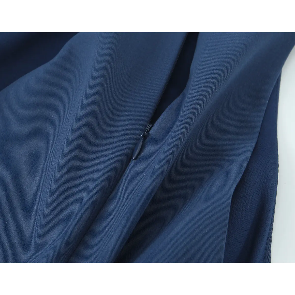  Close-up detail of the hidden center-back zipper on a navy blue halter-neck mini dress, showing the fabric texture and zipper pull.