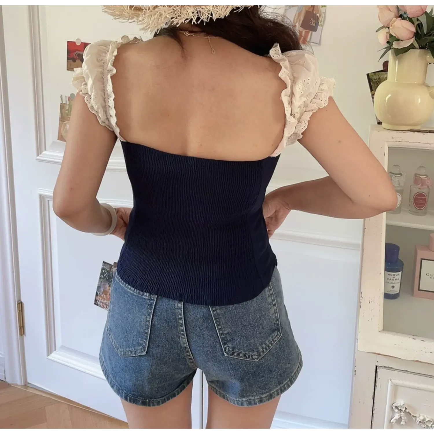 Lifestyle back shot of model wearing the navy blue lace-trimmed corset-style top