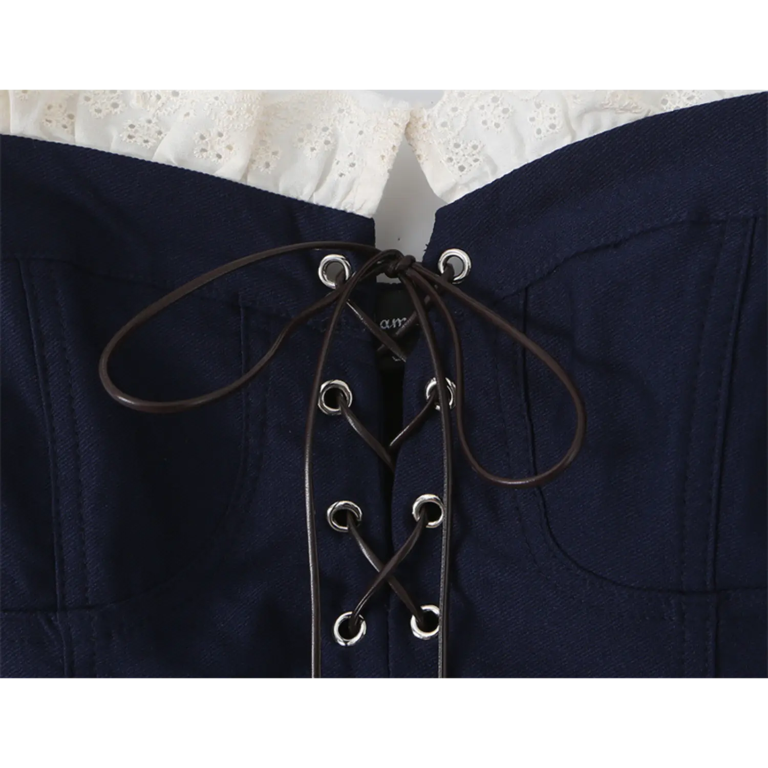 Close-up of the front lace-up closure and eyelets on the navy blue corset-style top