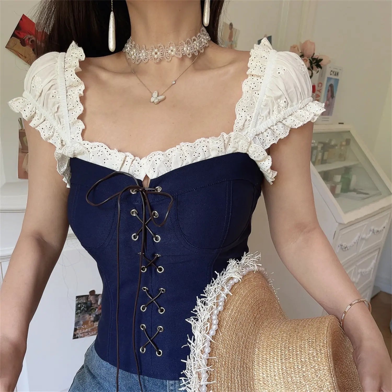 Lifestyle shot of model wearing the navy blue lace-trimmed corset-style top with jeans