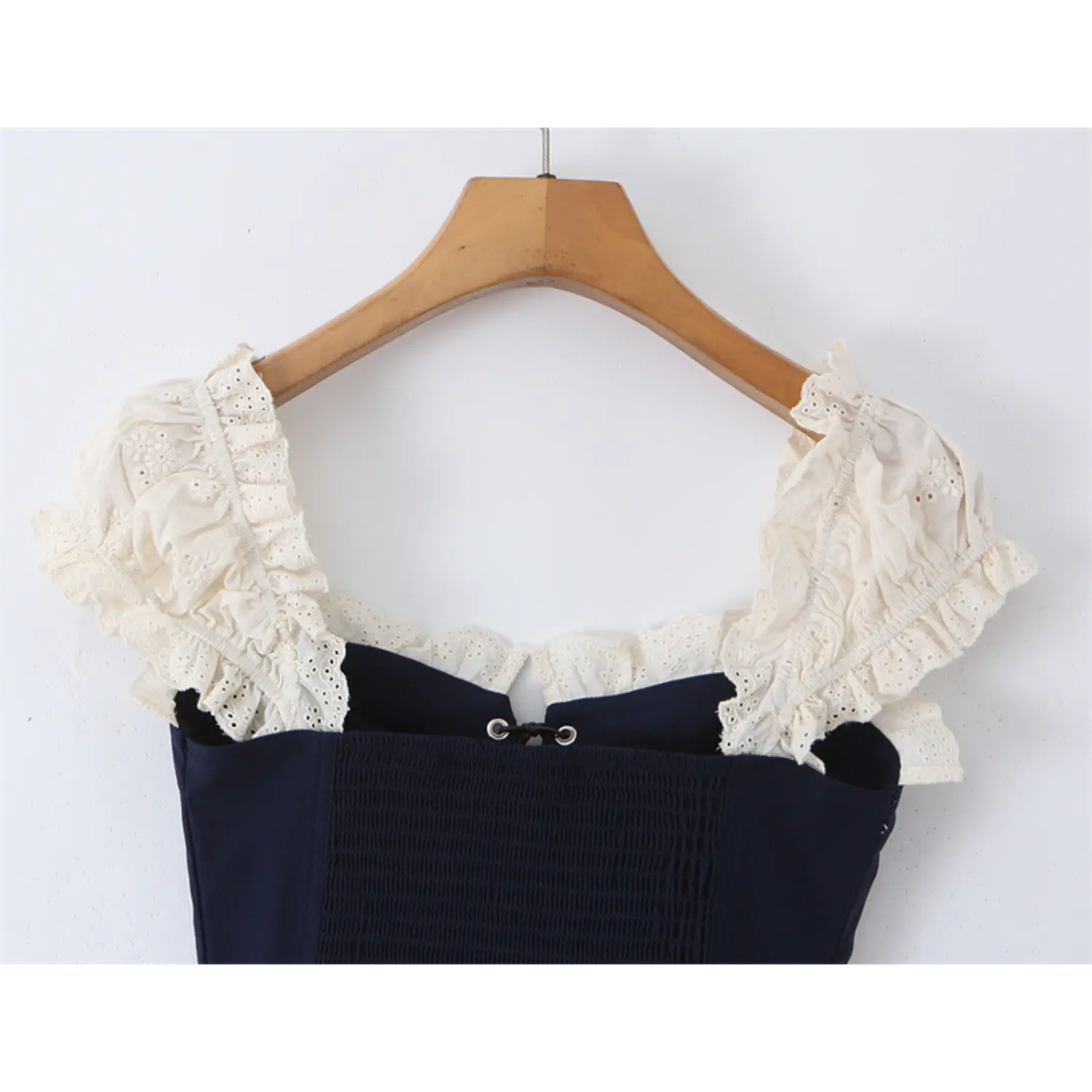 Close-up of the lace-trimmed square neckline on the navy blue corset-style top