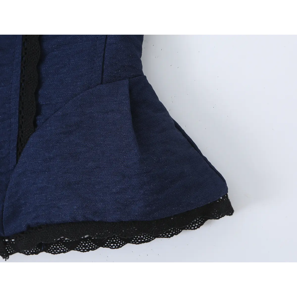 Close-up of the peplum hem, showing the scalloped black lace trim and flared silhouette.
