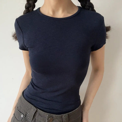 Lifestyle shot of form-fitting navy blue ribbed crew-neck short-sleeve t-shirt, tucked into jeans