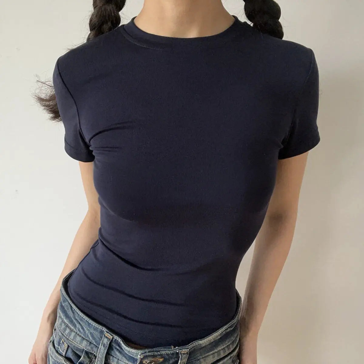 Lifestyle shot of form-fitting navy blue ribbed crew-neck t-shirt, tucked into jeans