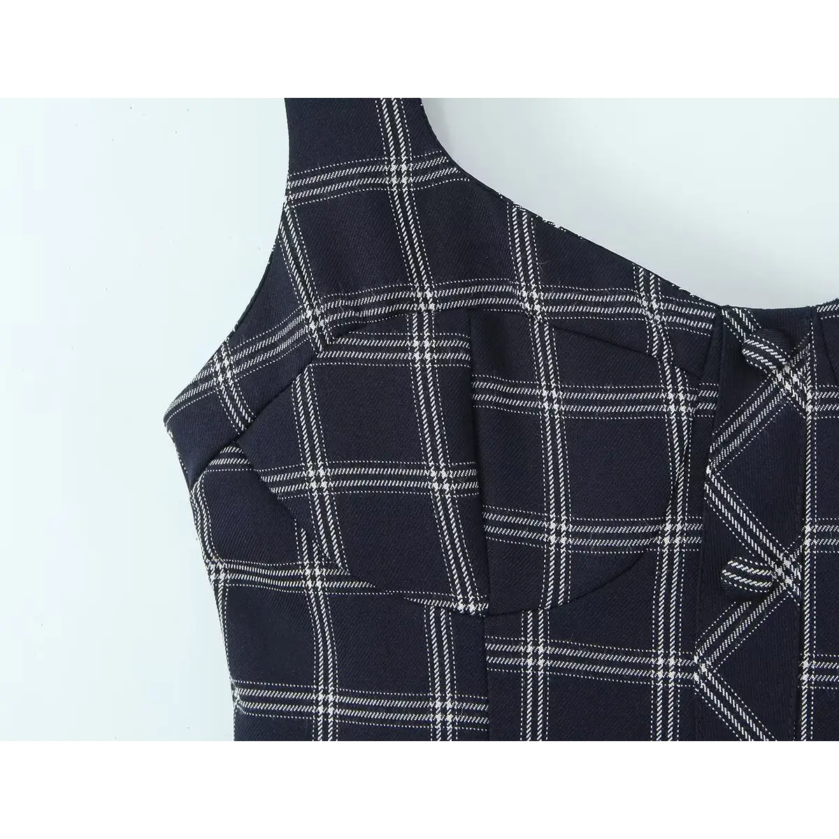 Close-up of the tailored side seams and checkered pattern on the navy cami dress