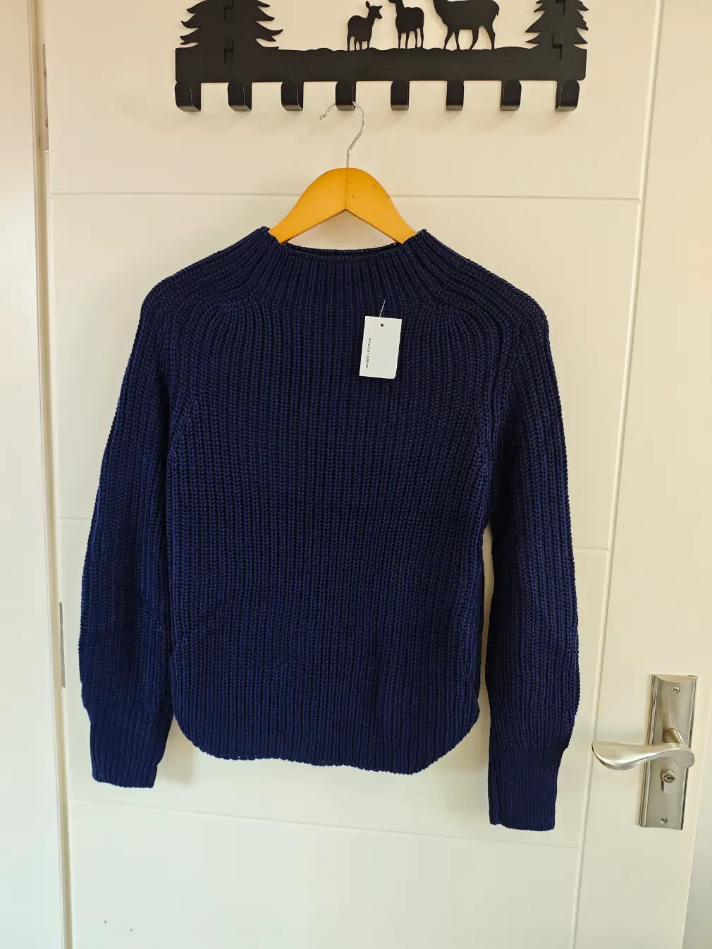 Navy chunky ribbed mock neck balloon sleeve sweater hanging on door, front view