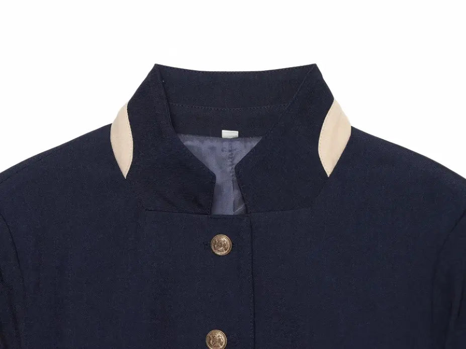 Close-up of stand collar with cream contrast trim and gold button