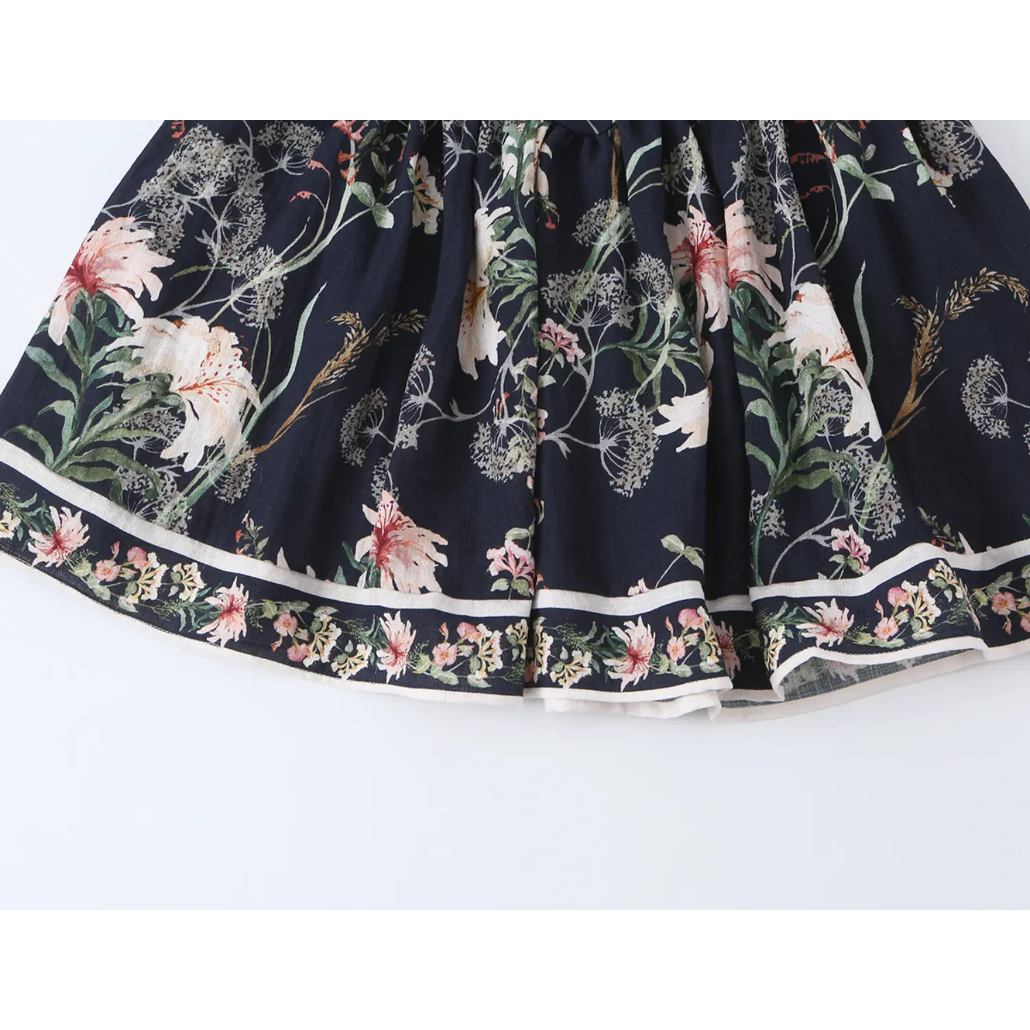 Top-down shot of flared skirt and printed hem trim of navy floral cami dress