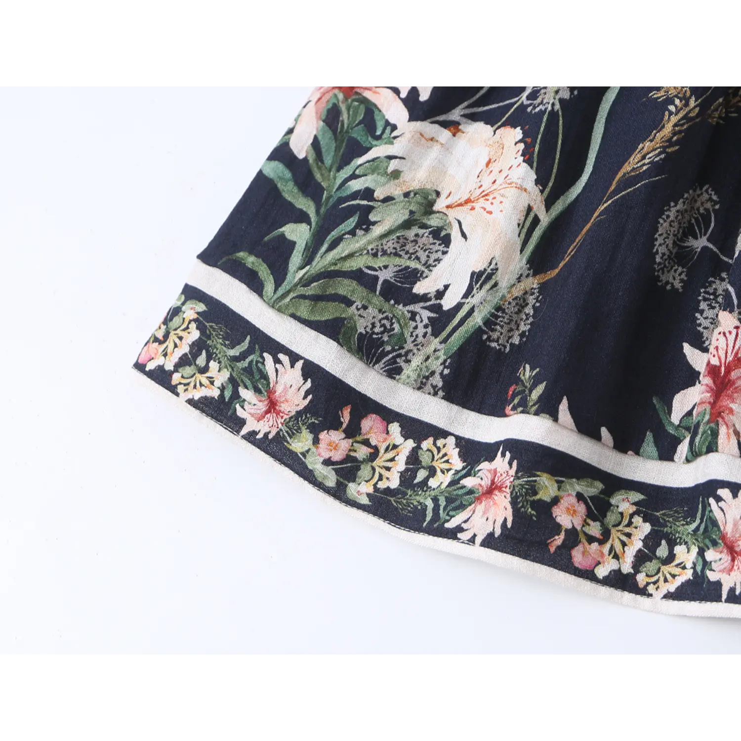 Close-up view of decorative floral border hem with white piping on navy floral mini dress