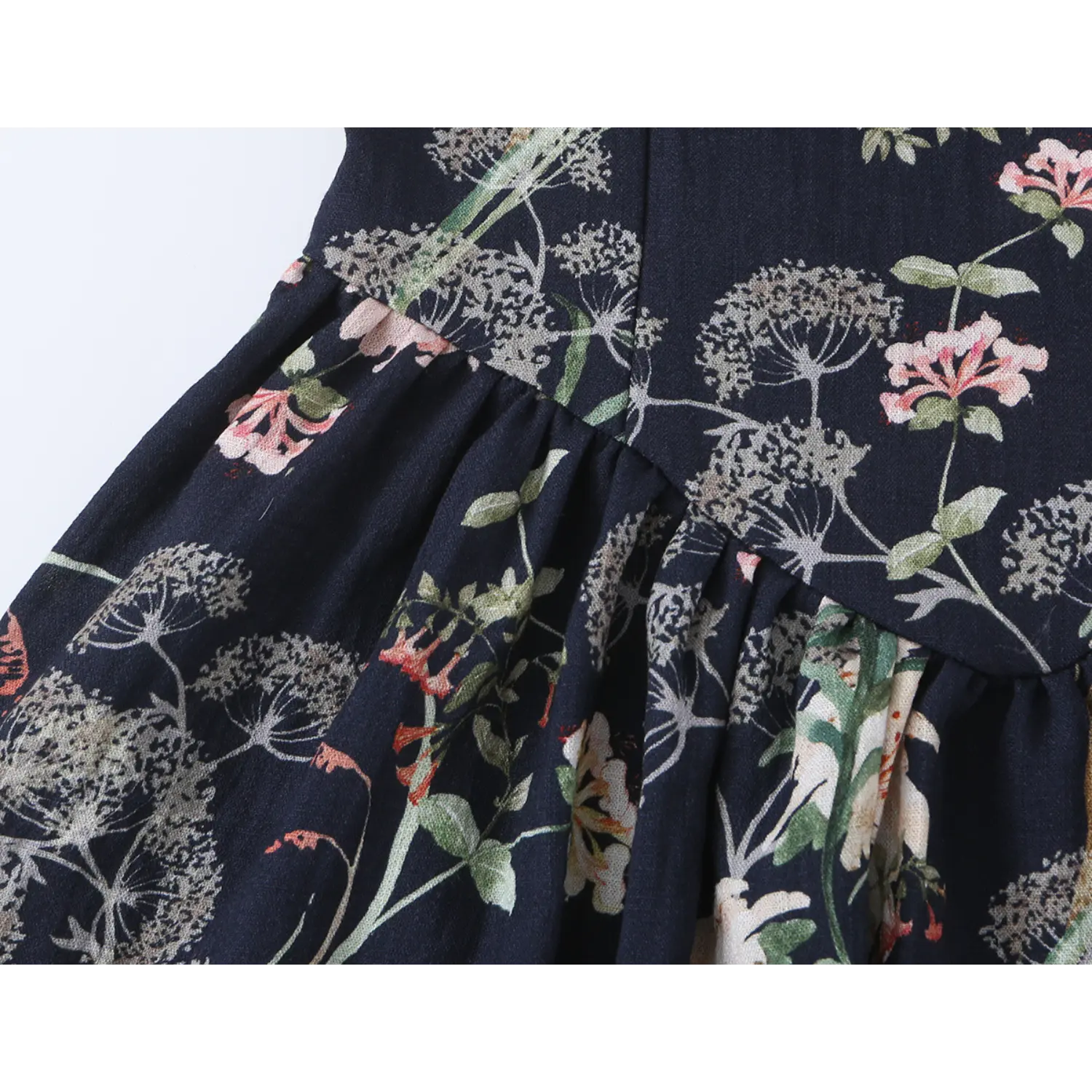 Close-up view of gathered seam connecting bodice and ruffled skirt on navy floral dress