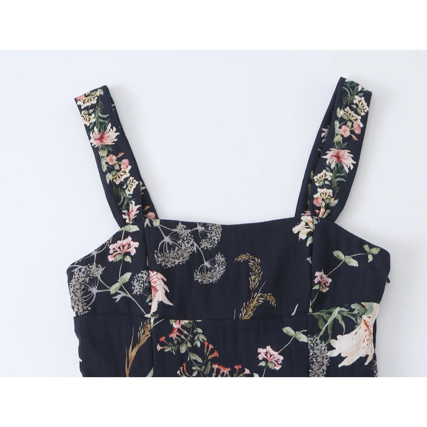 Close-up front neckline detail, wide printed shoulder straps and square neck of navy floral mini dress
