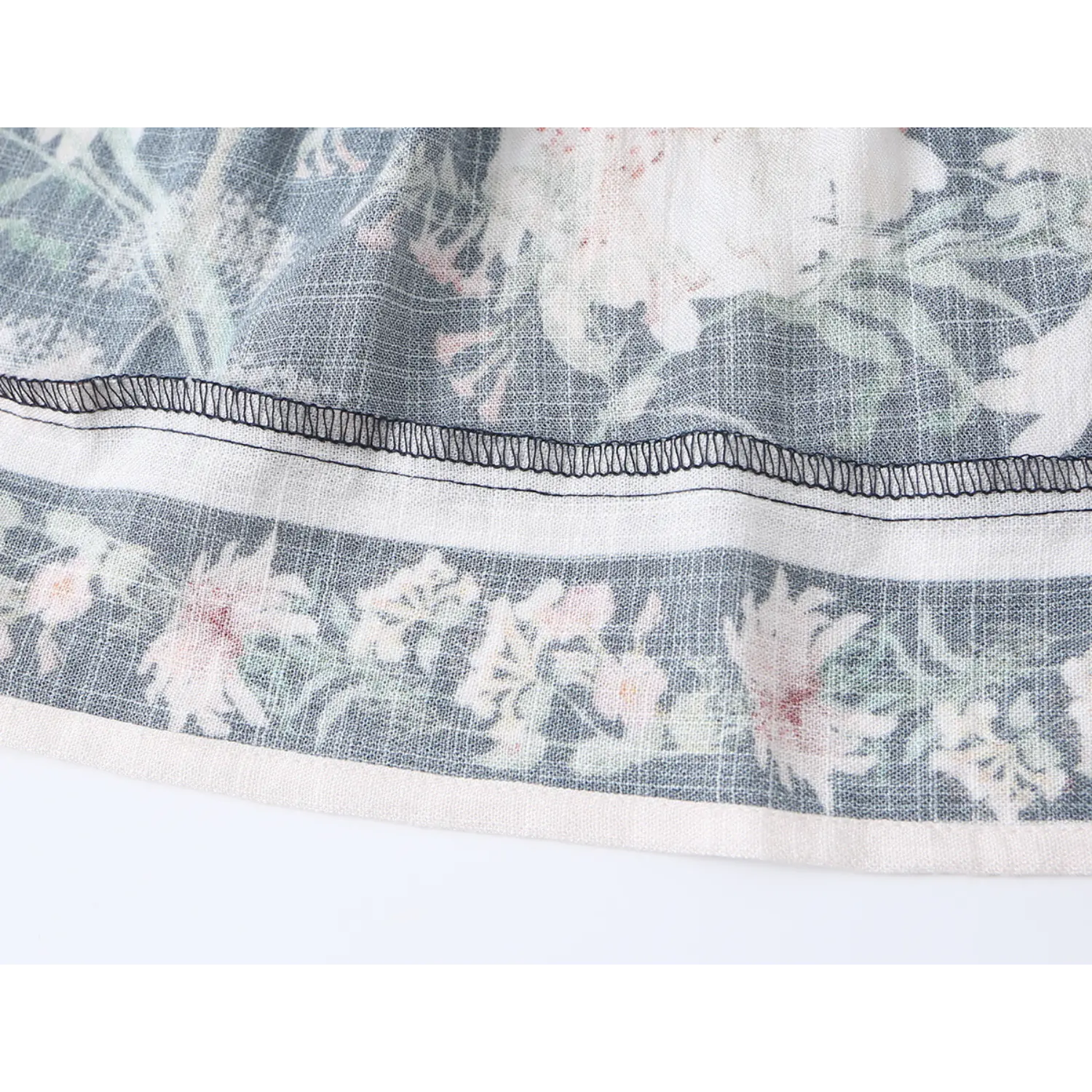 Extreme close-up of overlock stitching and floral hem border on dark navy fabric