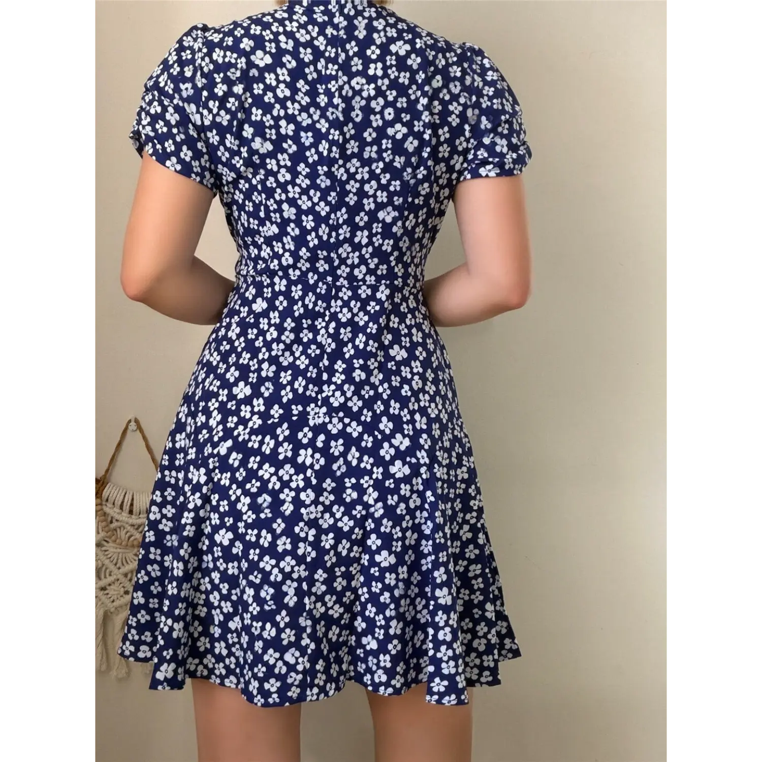 Lifestyle back view of model wearing the navy blue floral puff-sleeve dress