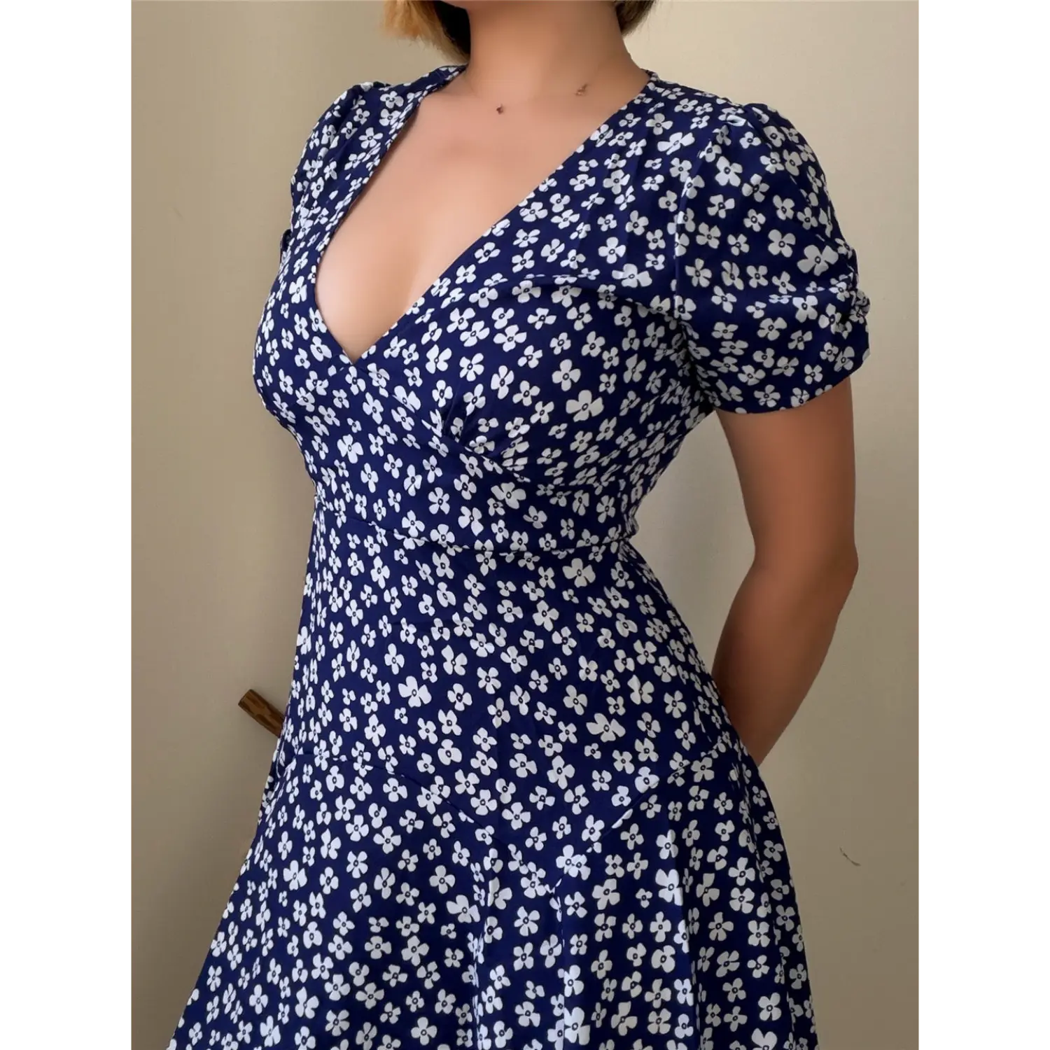 Close-up lifestyle shot of model wearing the navy blue floral puff-sleeve dress