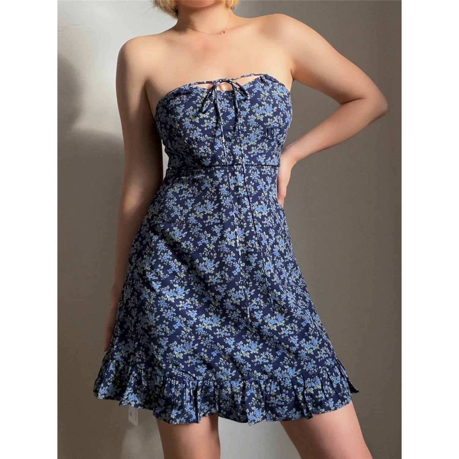 Lifestyle back view of model wearing the navy blue floral strapless dress, showing the tie detail at the back