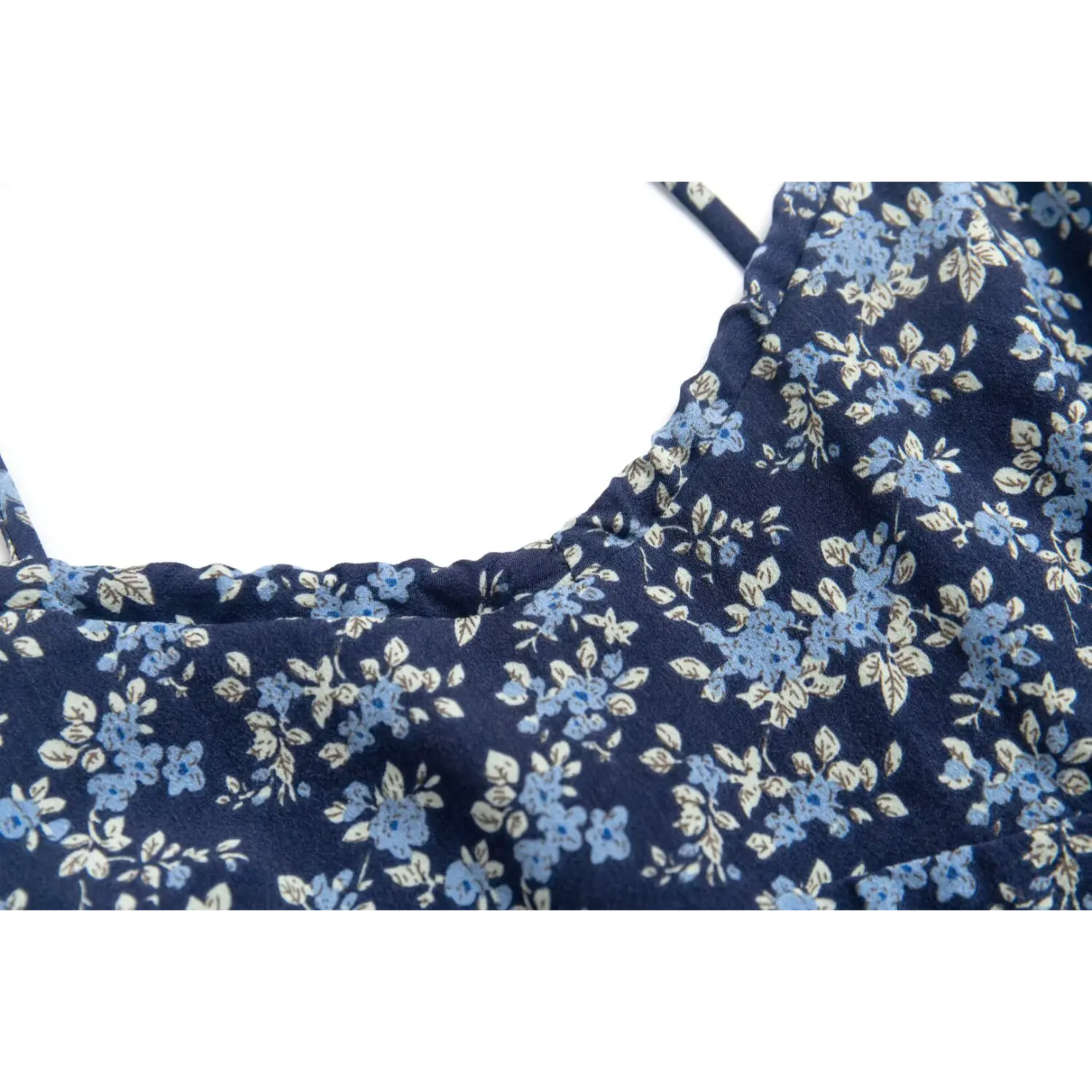 Close-up of the square neckline and floral print on the navy blue spaghetti strap dress
