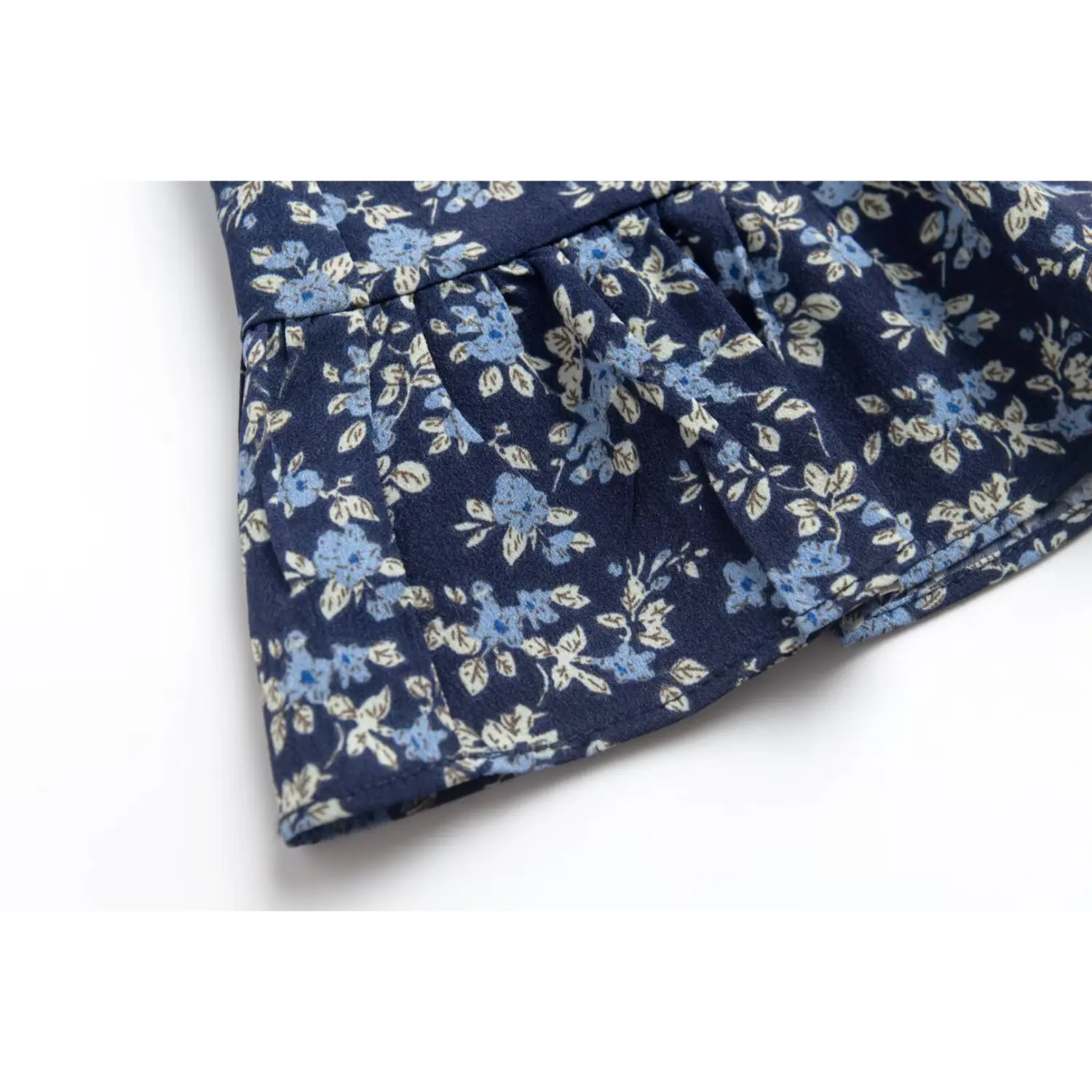 Close-up of the ruffled hem on the navy blue floral spaghetti strap dress