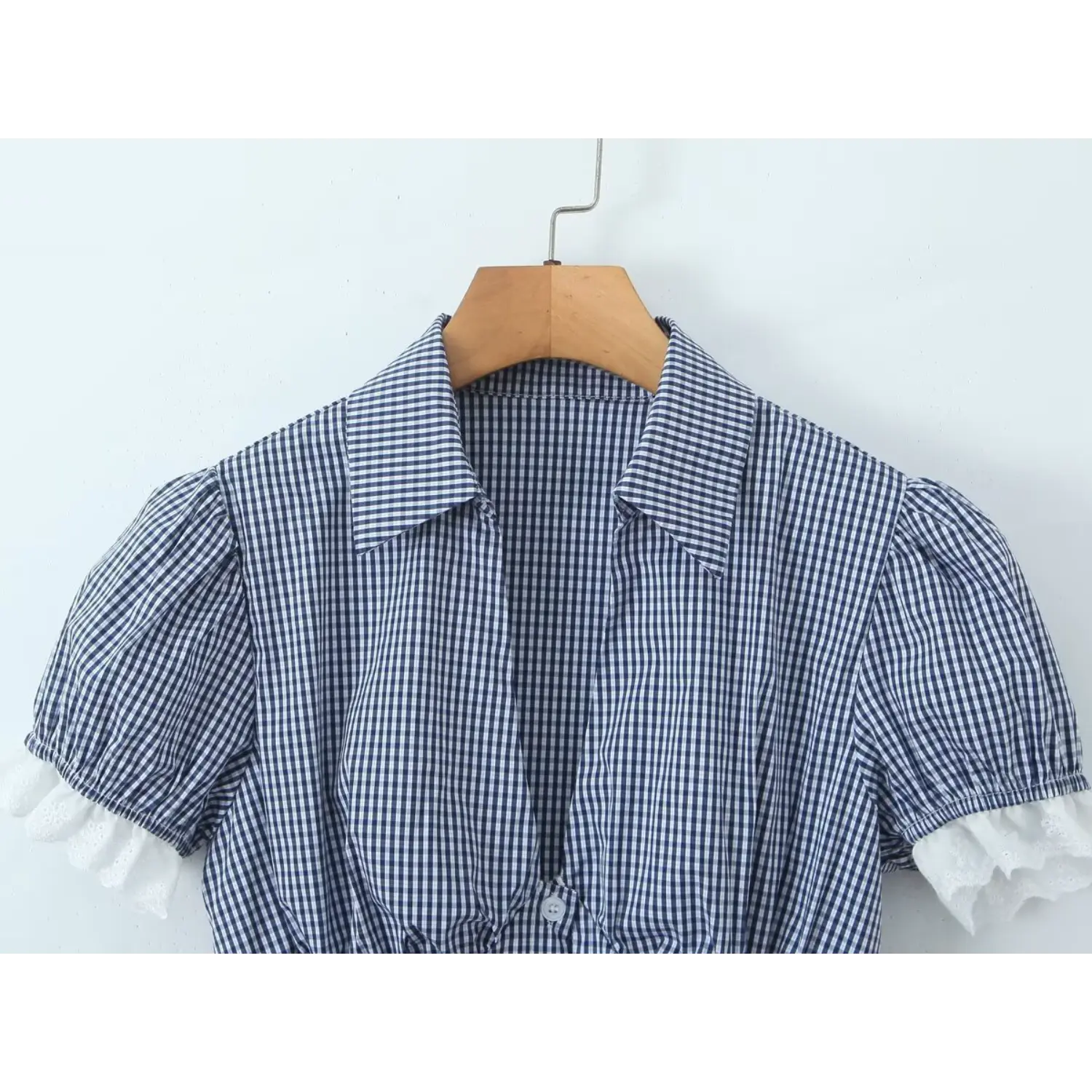 Navy small gingham V lapel crop top wooden hanger front shot, V neck placket bust gathering shaping puff elastic short sleeves white eyelet lace trim on cuffs & hem slim cropped check blouse single piece display