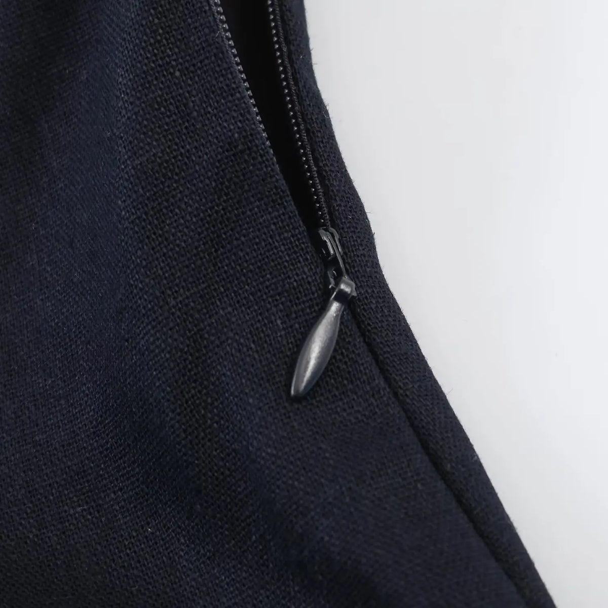 Close-up of invisible side zipper on navy halter mini dress, woven fabric texture