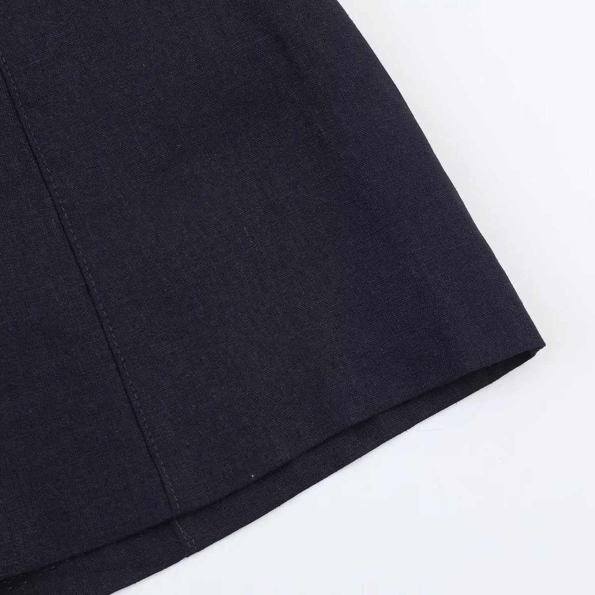 Partial shot of navy woven fabric skirt of halter mini dress, showing texture and stitching lines