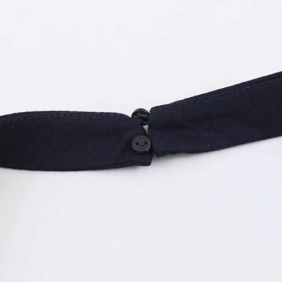 Close-up of buckle button closure on halter neck strap of navy mini dress