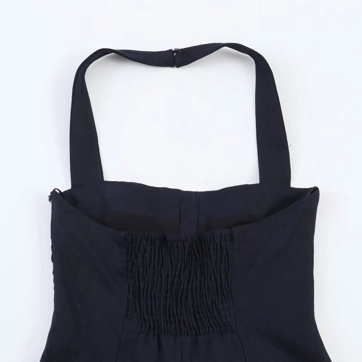 Close-up of smocked elastic back panel on navy halter mini dress, stretch gathered fabric