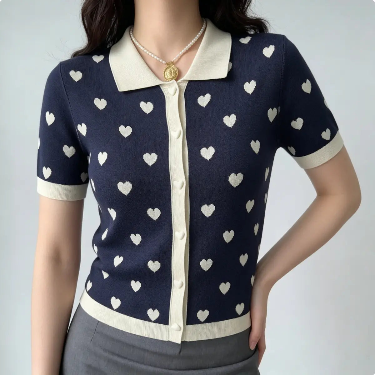 Model wearing navy heart print knit polo cardigan, featuring cream contrast trim and heart-shaped buttons.