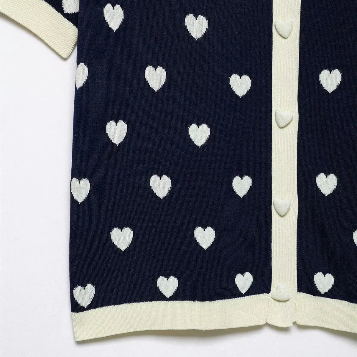 Close-up of the heart-shaped buttons on navy knit polo top, showing contrast placket and trim.