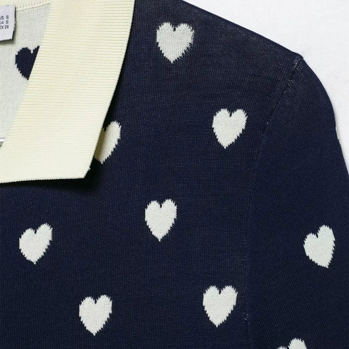 Close-up of the polo collar on navy heart print knit top, showing contrast trim and heart pattern.