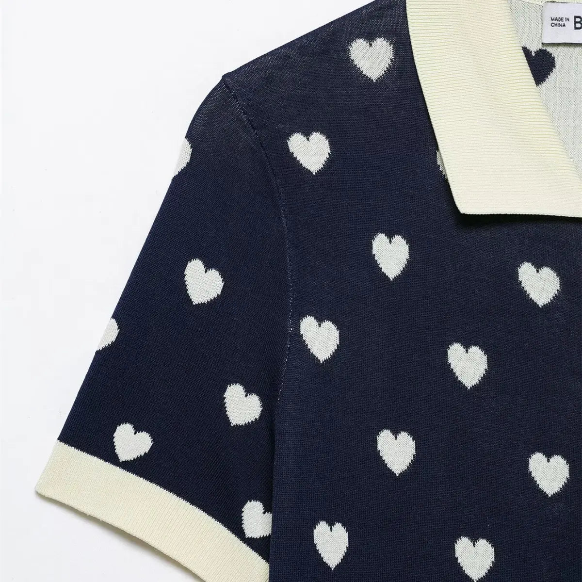 Close-up of the sleeve on navy heart print knit polo top, showing contrast cuff and heart pattern.