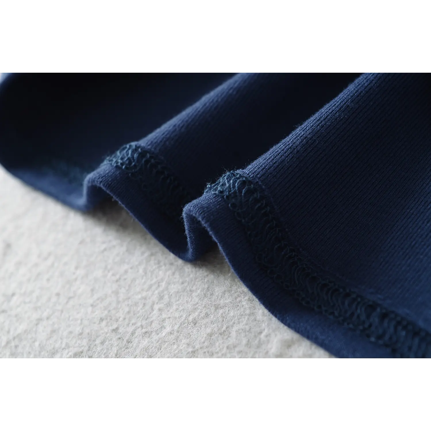 Close‑up shot of hem scalloped lace stitching detail on navy blue off‑shoulder long sleeve lace top