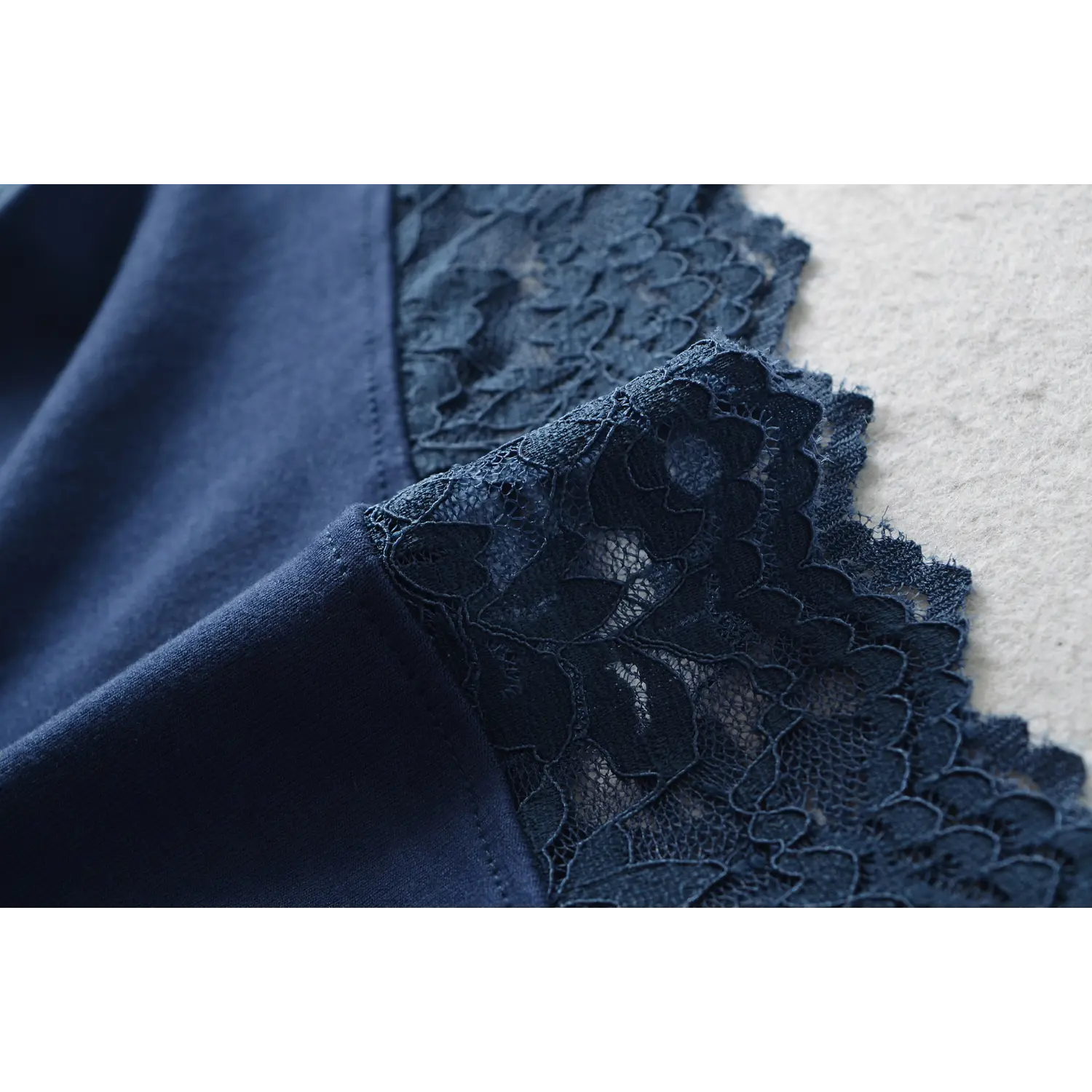 Macro close‑up of floral lace overlay and soft knit lining fabric for navy off‑shoulder top