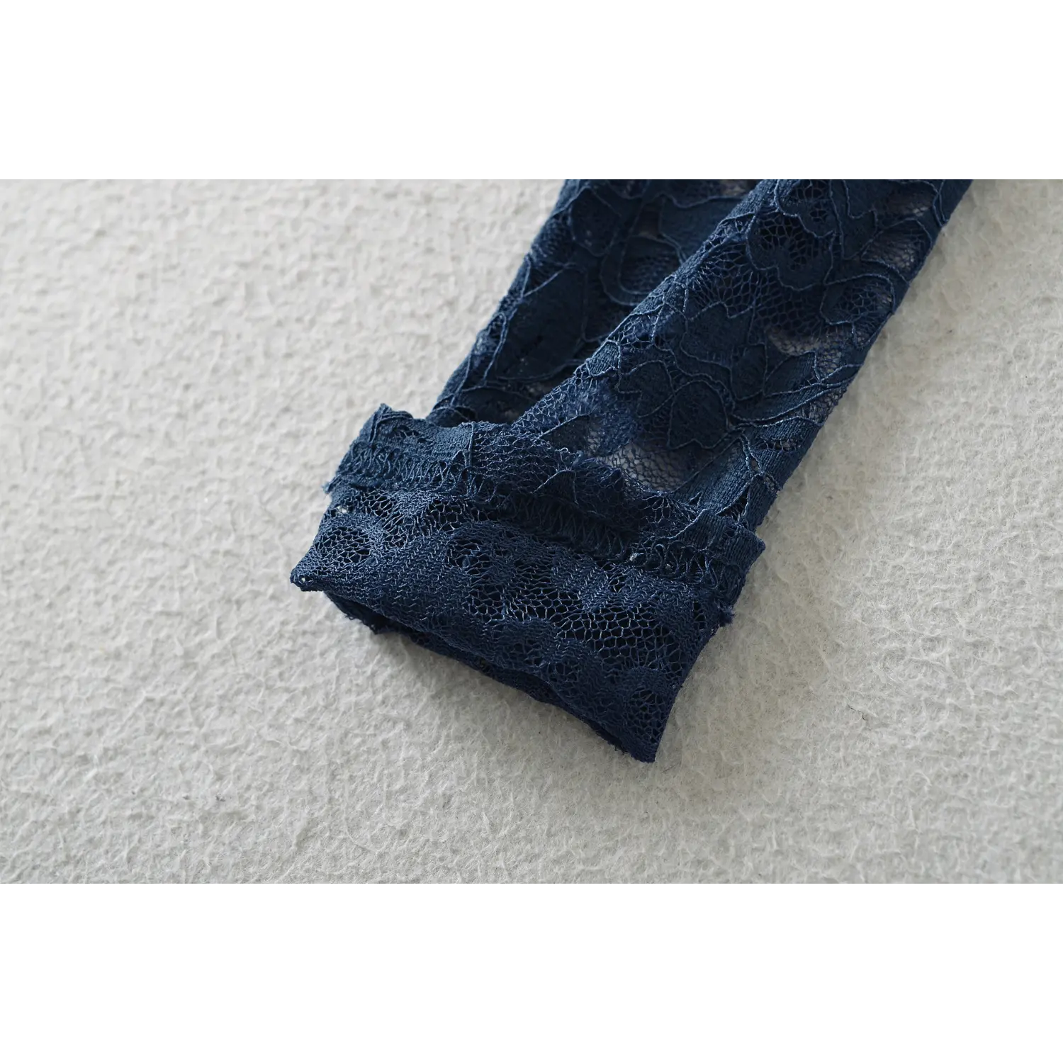 Close‑up view of finished lace sleeve cuff stitching detail on navy off‑shoulder long sleeve top
