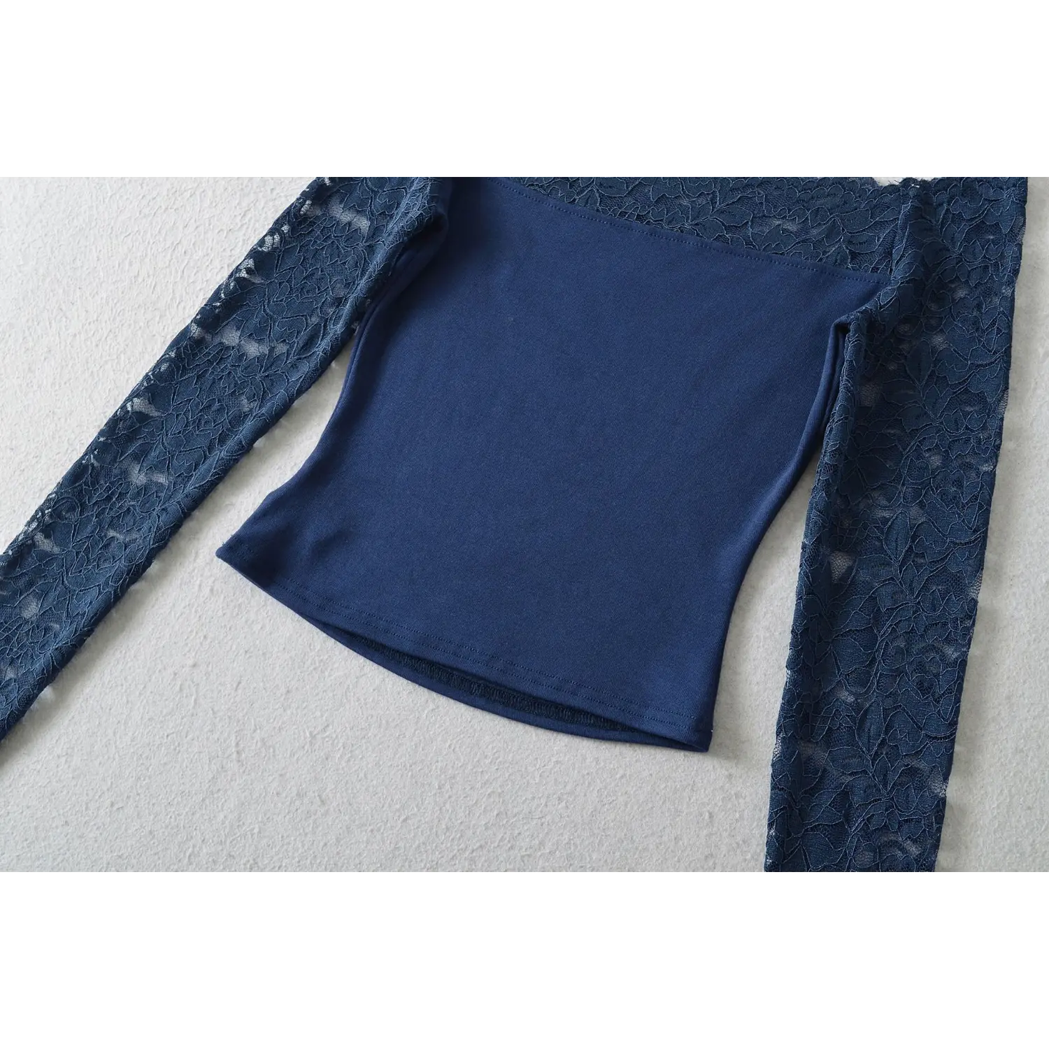 Flat lay full view navy off‑shoulder lace long sleeve cropped top, showing fitted waist and finished bottom hem