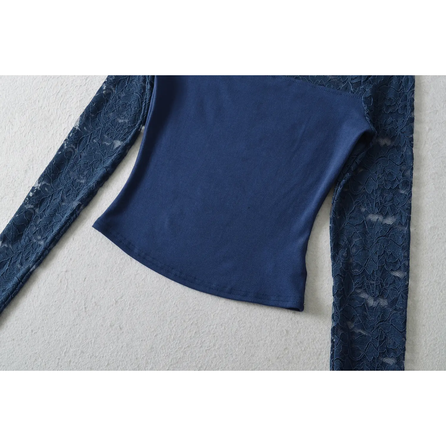 Flat close‑up showing fitted waist and finished bottom hem of navy off‑shoulder lace crop top