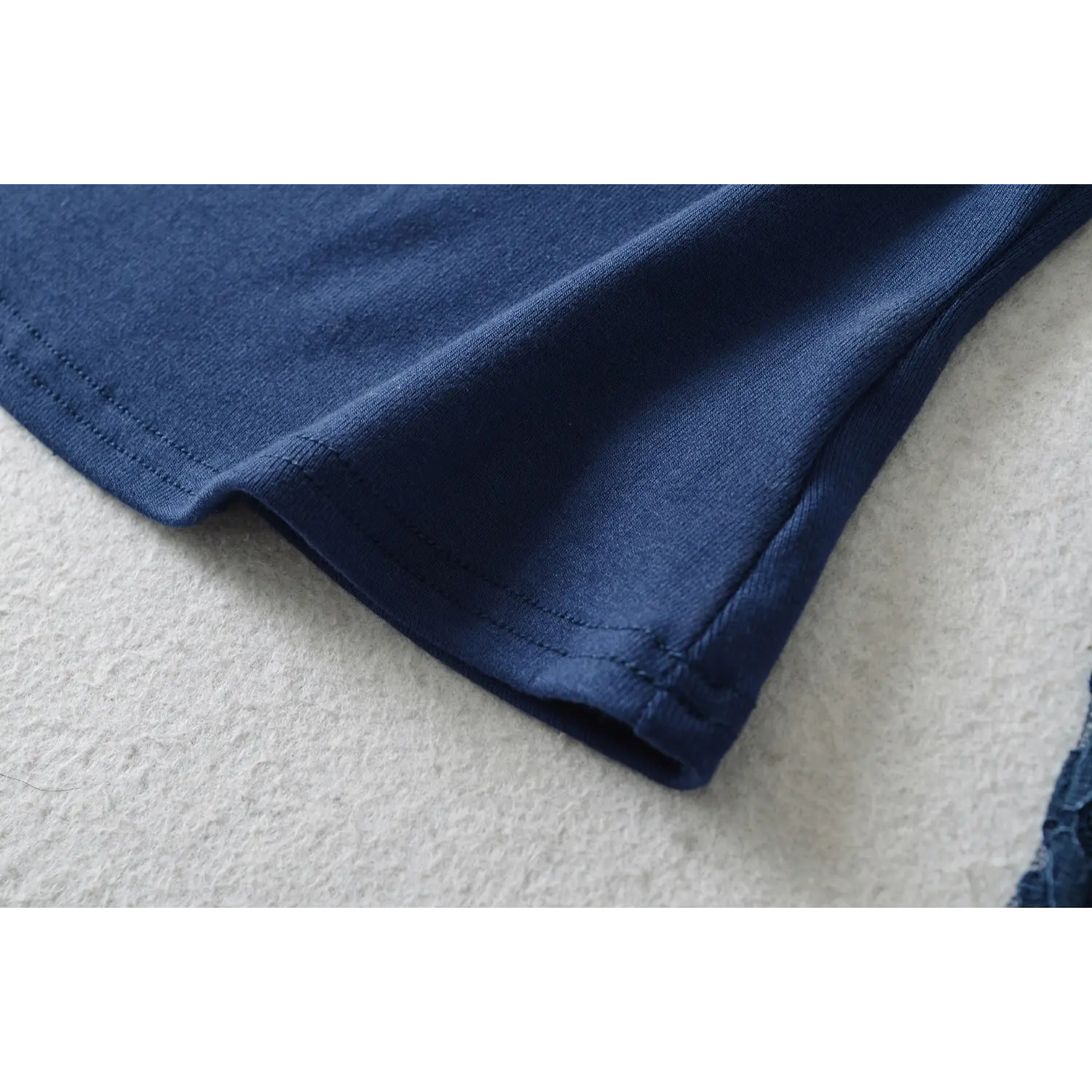 Close‑up of finished bottom hem stitching on navy blue off‑shoulder lace long sleeve crop top