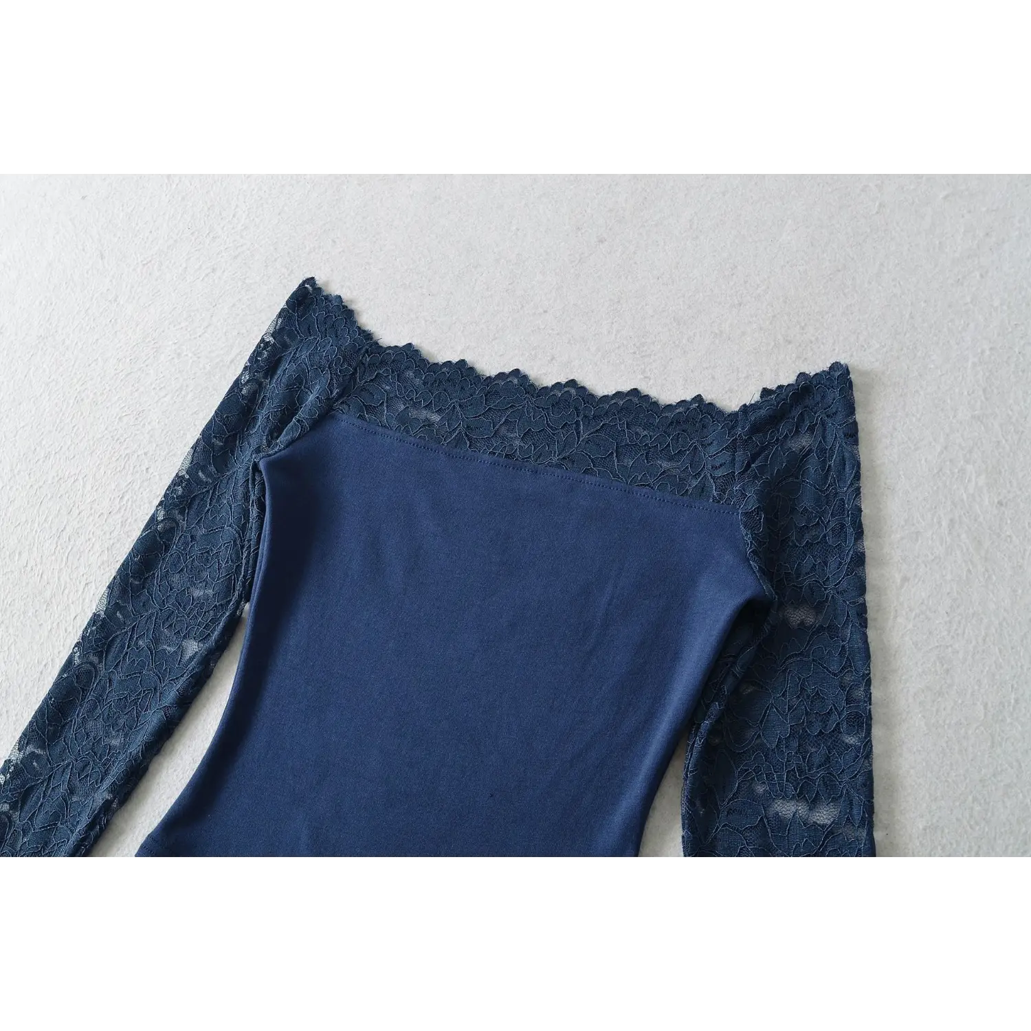 Close‑up detail of scalloped floral lace off‑the‑shoulder neckline on navy blue lace top