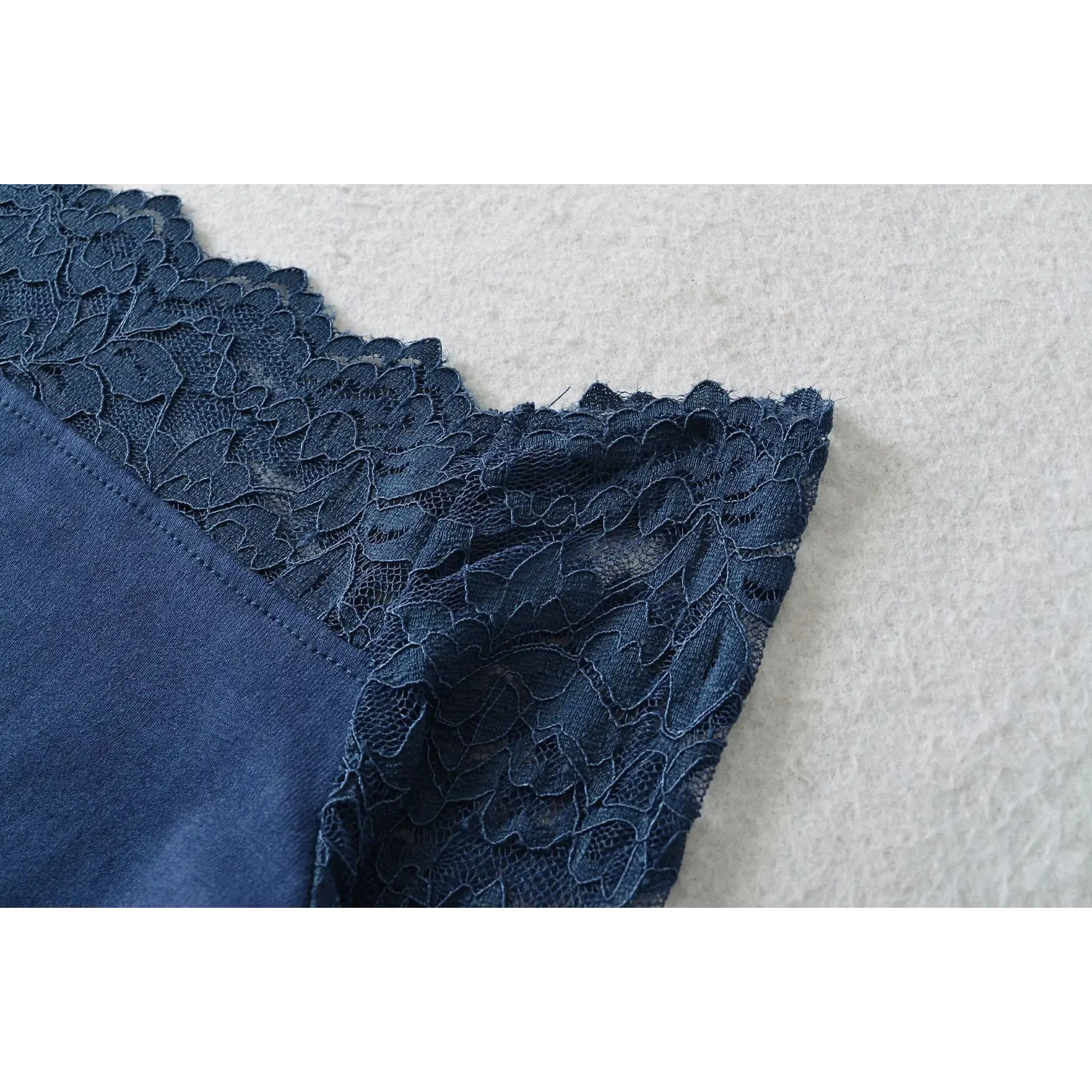 Detailed shot of scalloped lace trim edge at neckline of navy blue off‑shoulder lace blouse