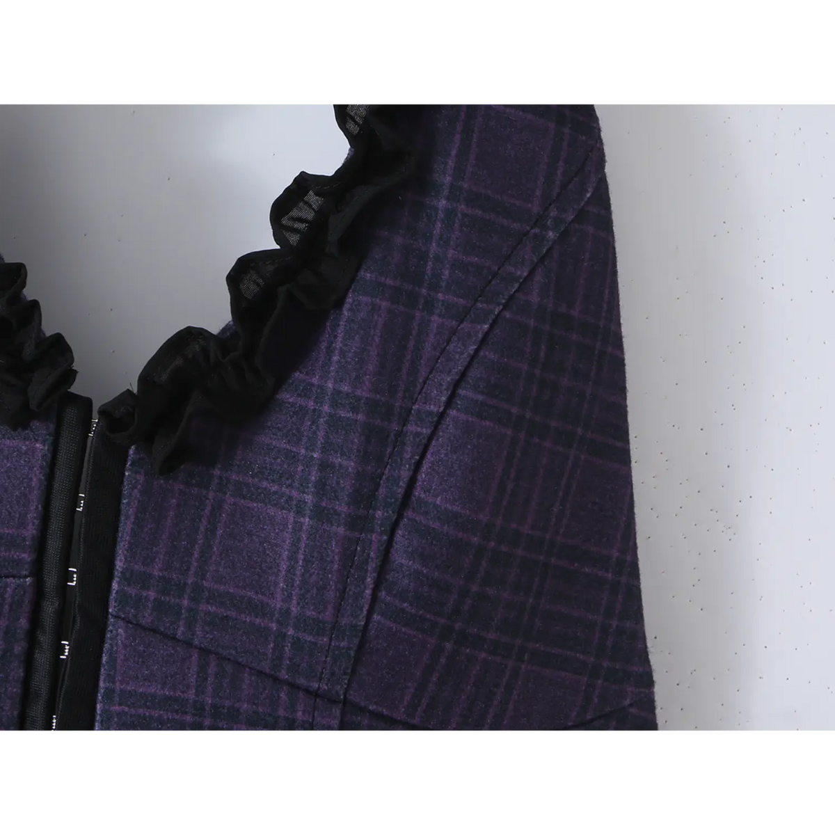 Fabric close-up showing black ruffle trim and navy tartan plaid texture of halter dress