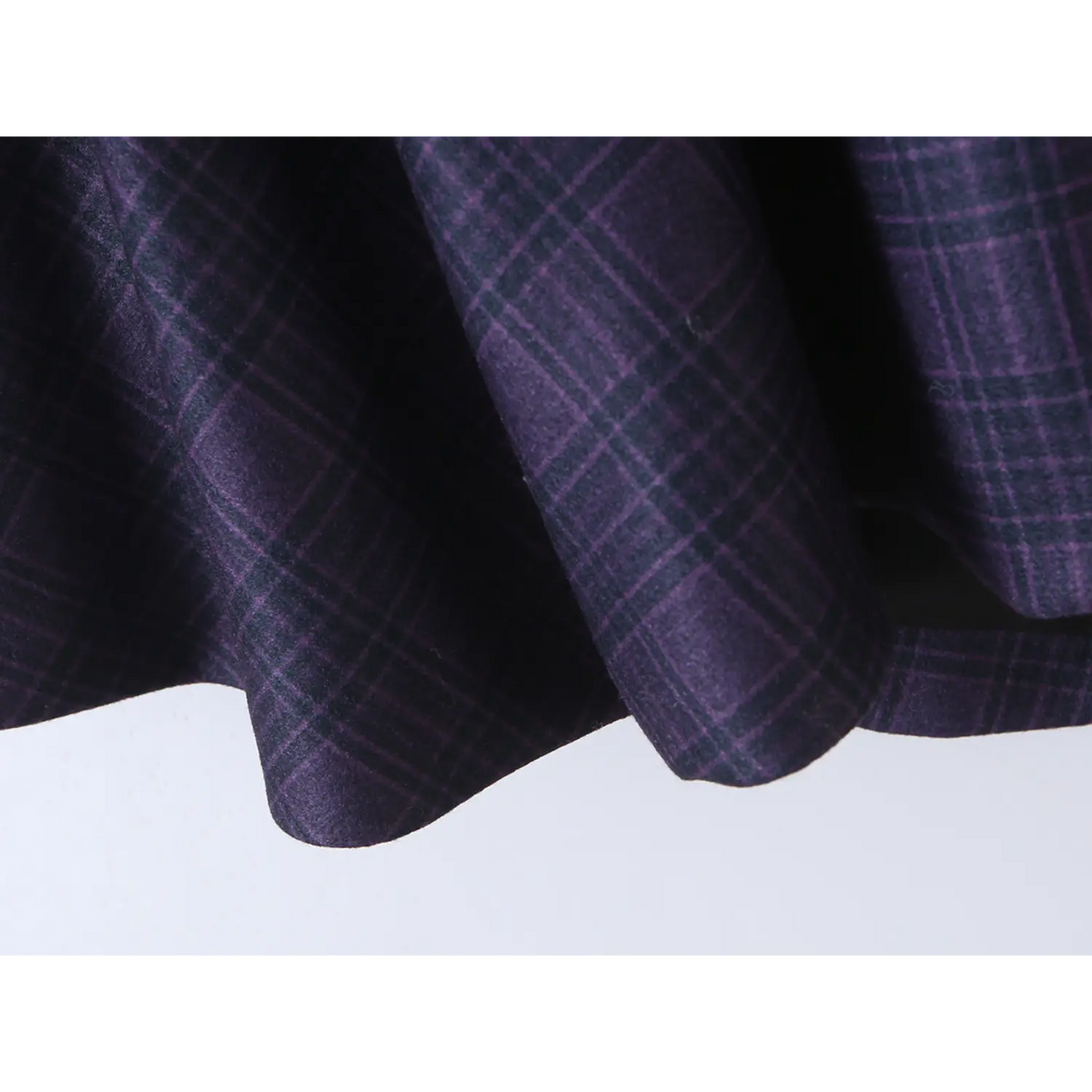 Close-up of flared skirt fabric, navy tartan plaid texture and drape of halter mini dress