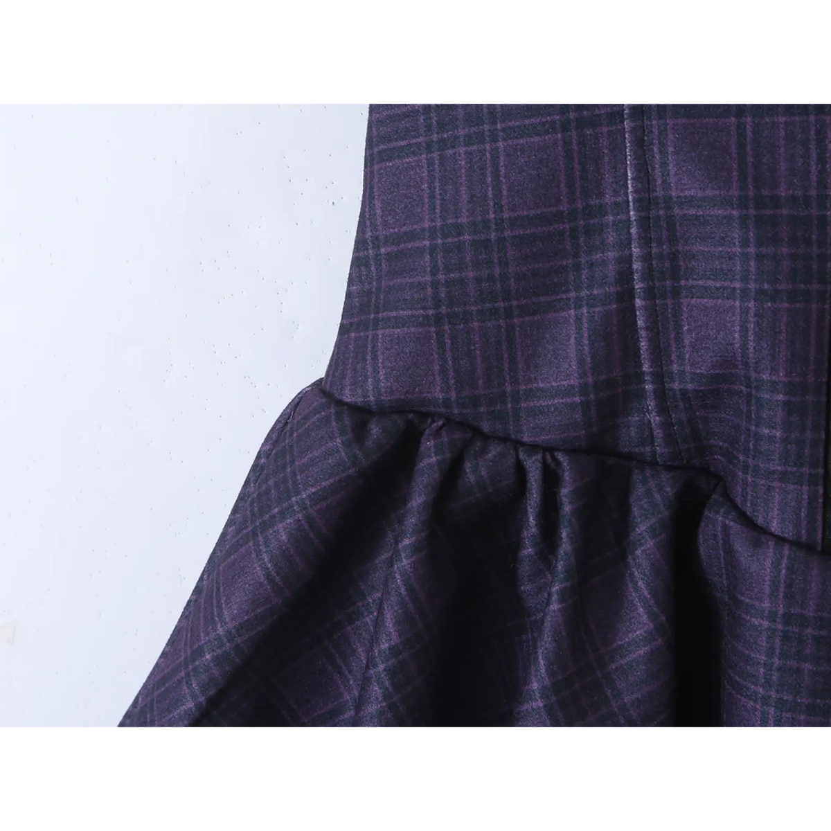 Close-up at waist seam connecting corset bodice and flared ruffle skirt on navy plaid halter dress