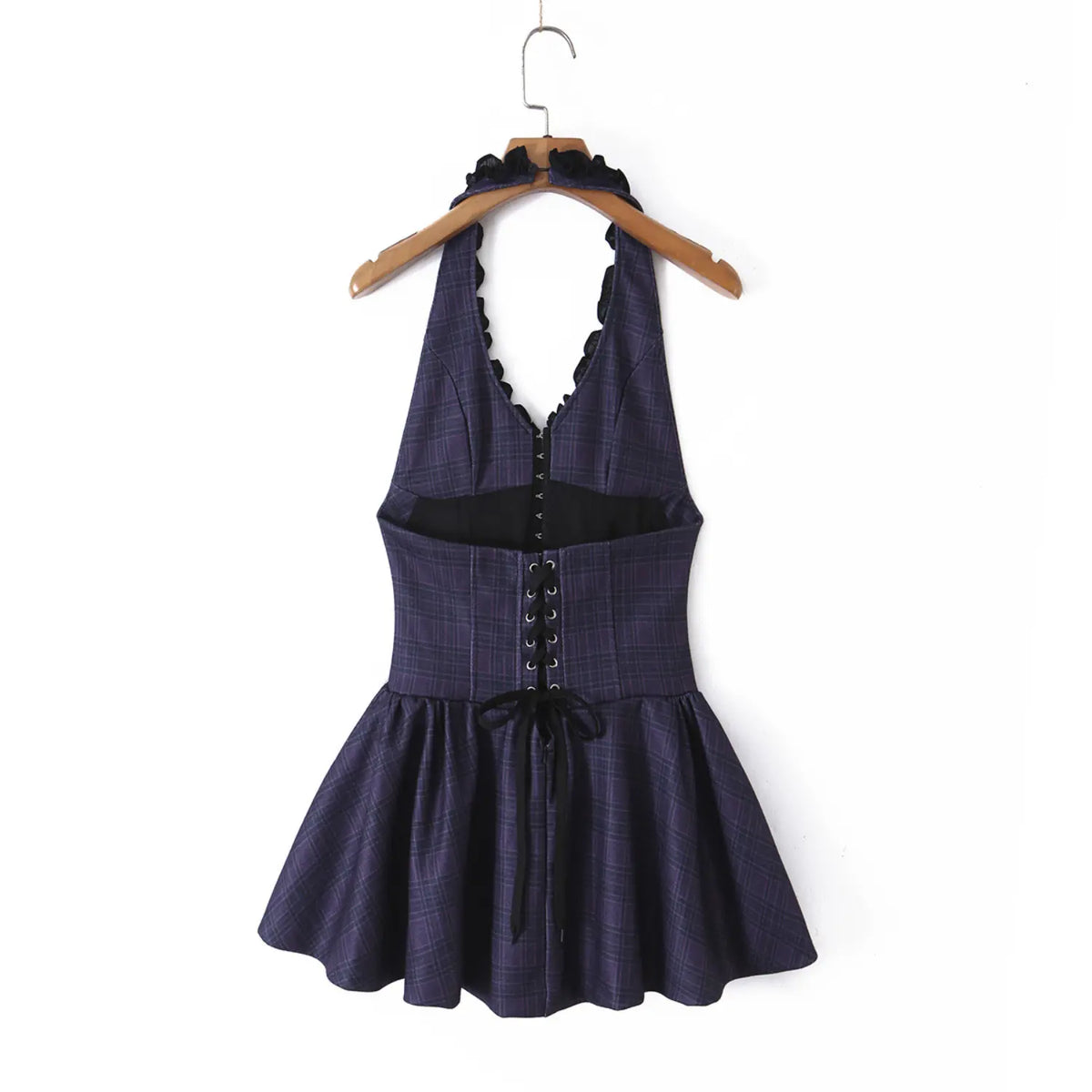 Back view of navy plaid halter mini dress with black ruffle neckline and lace-up corset back, hanging on wooden hanger