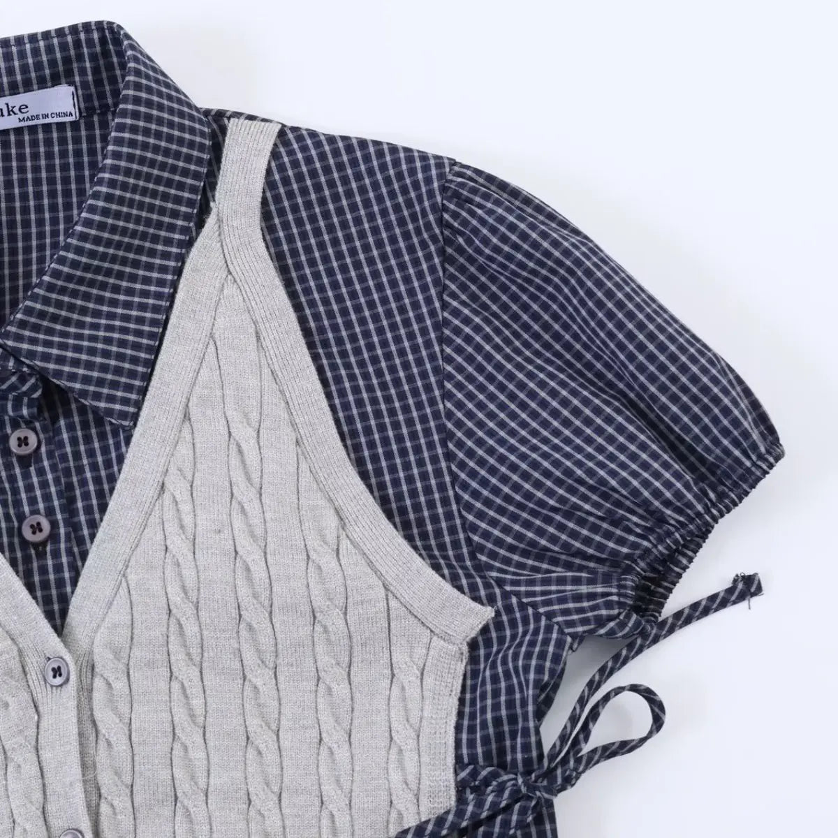 Navy plaid shirt with grey cable knit vest overlay, featuring puffed sleeves and side ties