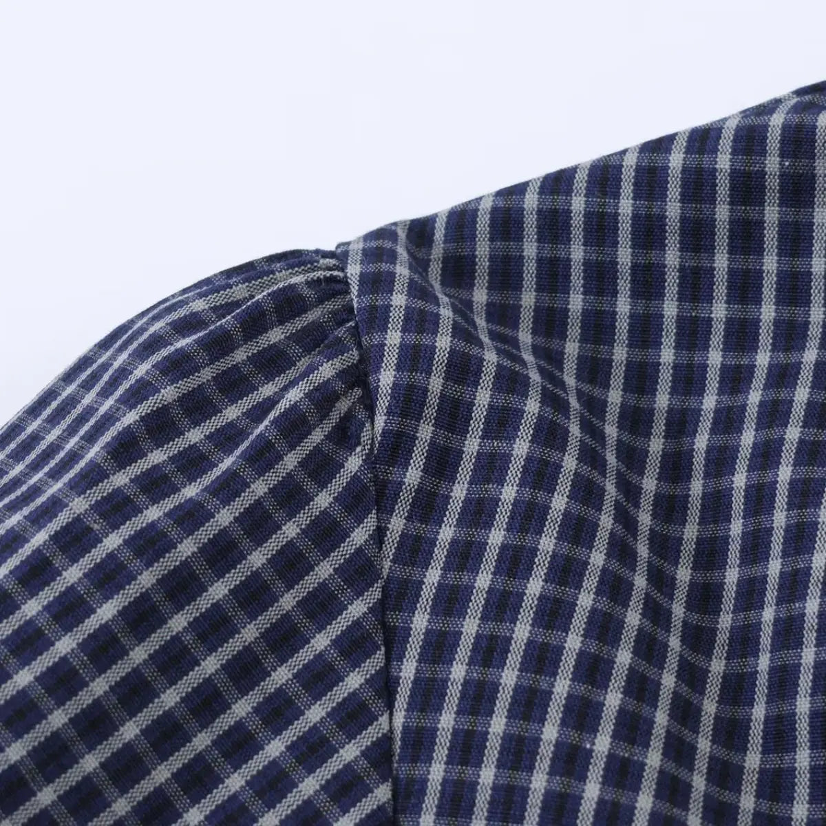 Close-up of the puffed sleeve on the navy plaid shirt, showing the gathered seam
