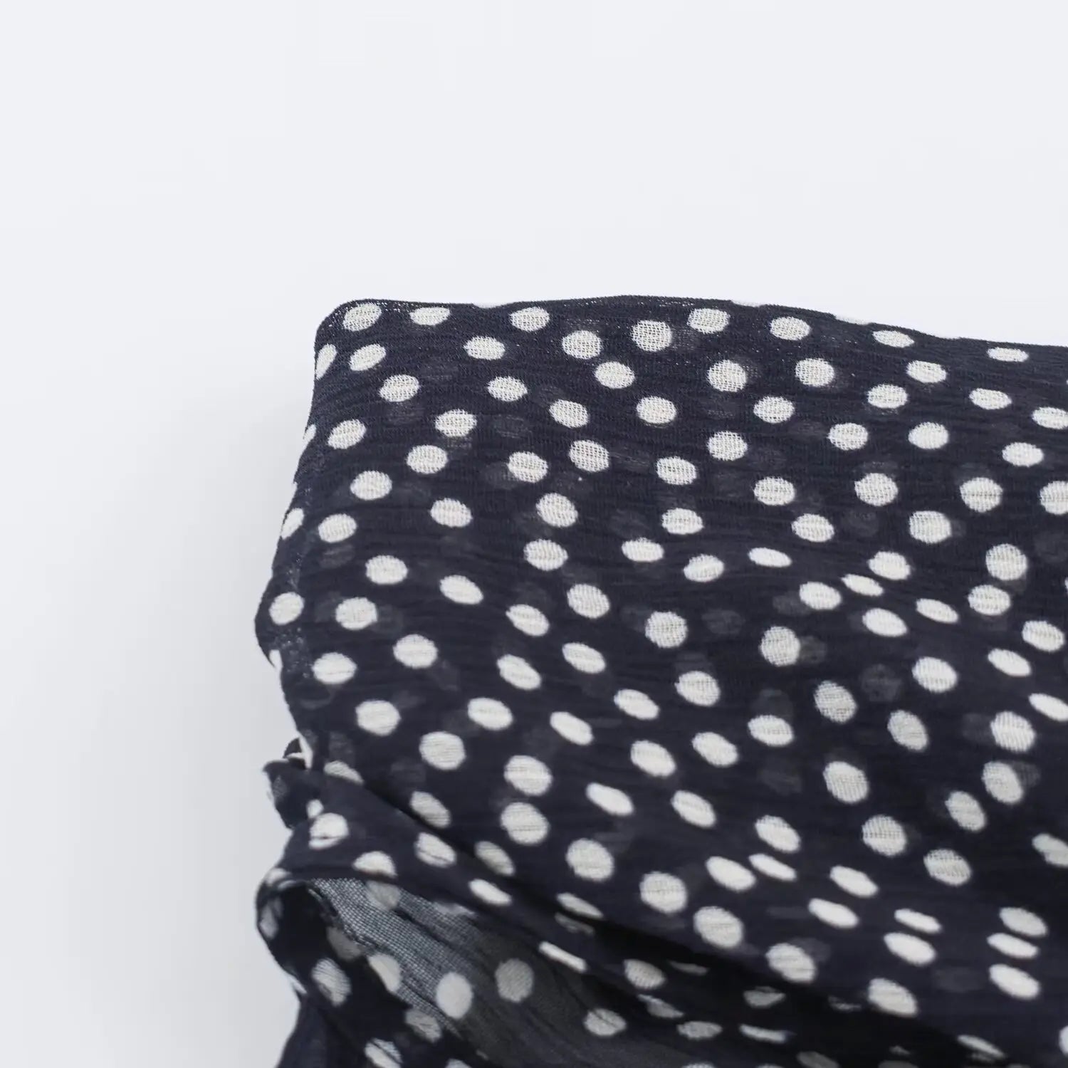 Macro shot of crinkled chiffon fabric with white polka dot print on navy maxi dress