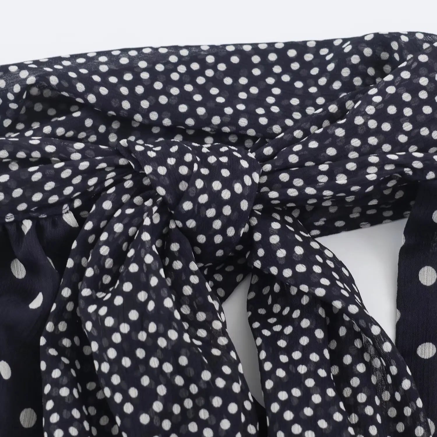 Close‑up of knotted halter neck tie detail on navy polka dot chiffon maxi dress