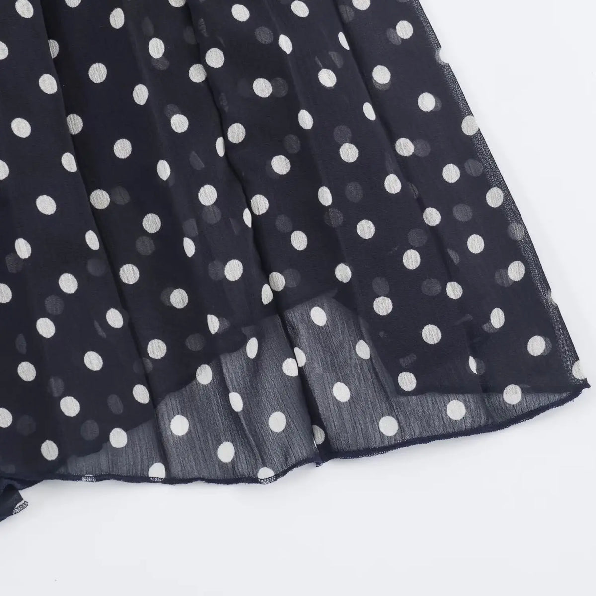 Close‑up of chiffon hem edge on navy polka dot pleated maxi dress