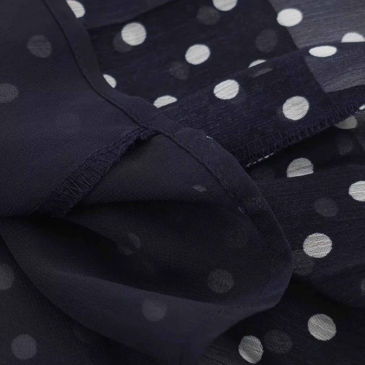 Close‑up of lining and seam stitching on navy blue polka dot chiffon halter maxi dress