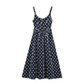 Flat‑lay front view of navy blue polka dot maxi dress, smocked spaghetti straps, v‑neck, waist bow tie, contrast white piping, a‑line maxi skirt