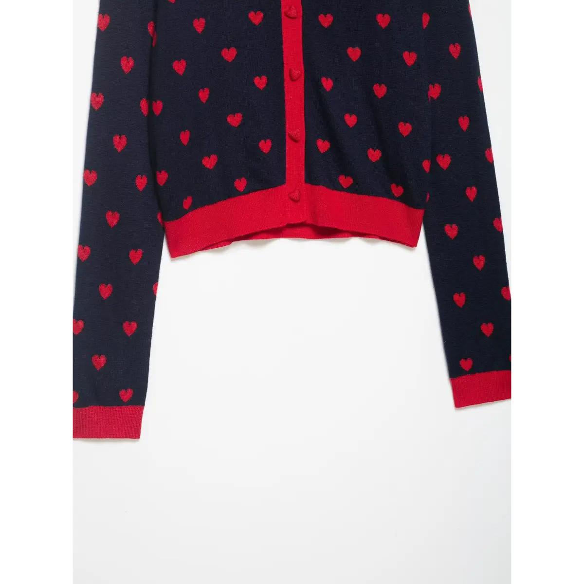 Front view of a navy and red heart-patterned cardigan with red trim and heart-shaped buttons.
